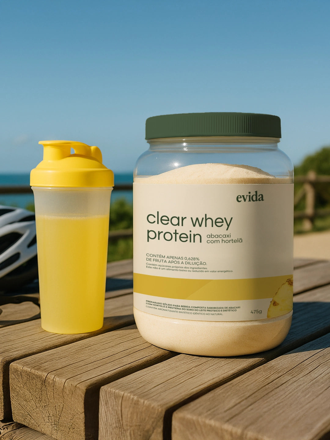 Clear whey protein powder container and yellow shaker bottle placed on wooden surface outdoors with blue sky background.
