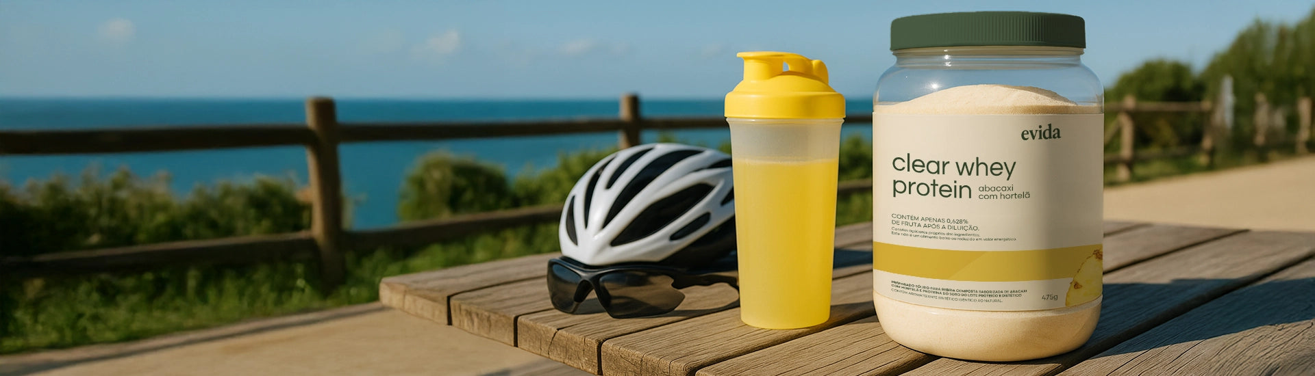 Container of clear whey protein and yellow shaker bottle on a wooden bench with a bike helmet and outdoor scenery in the background